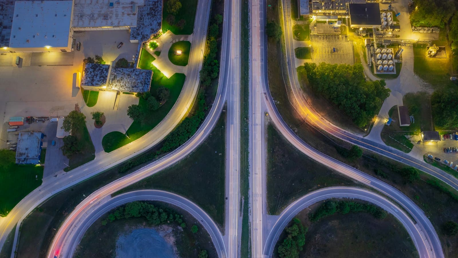 Aerial night view of a highway interchange with curved ramps branching off a straight road