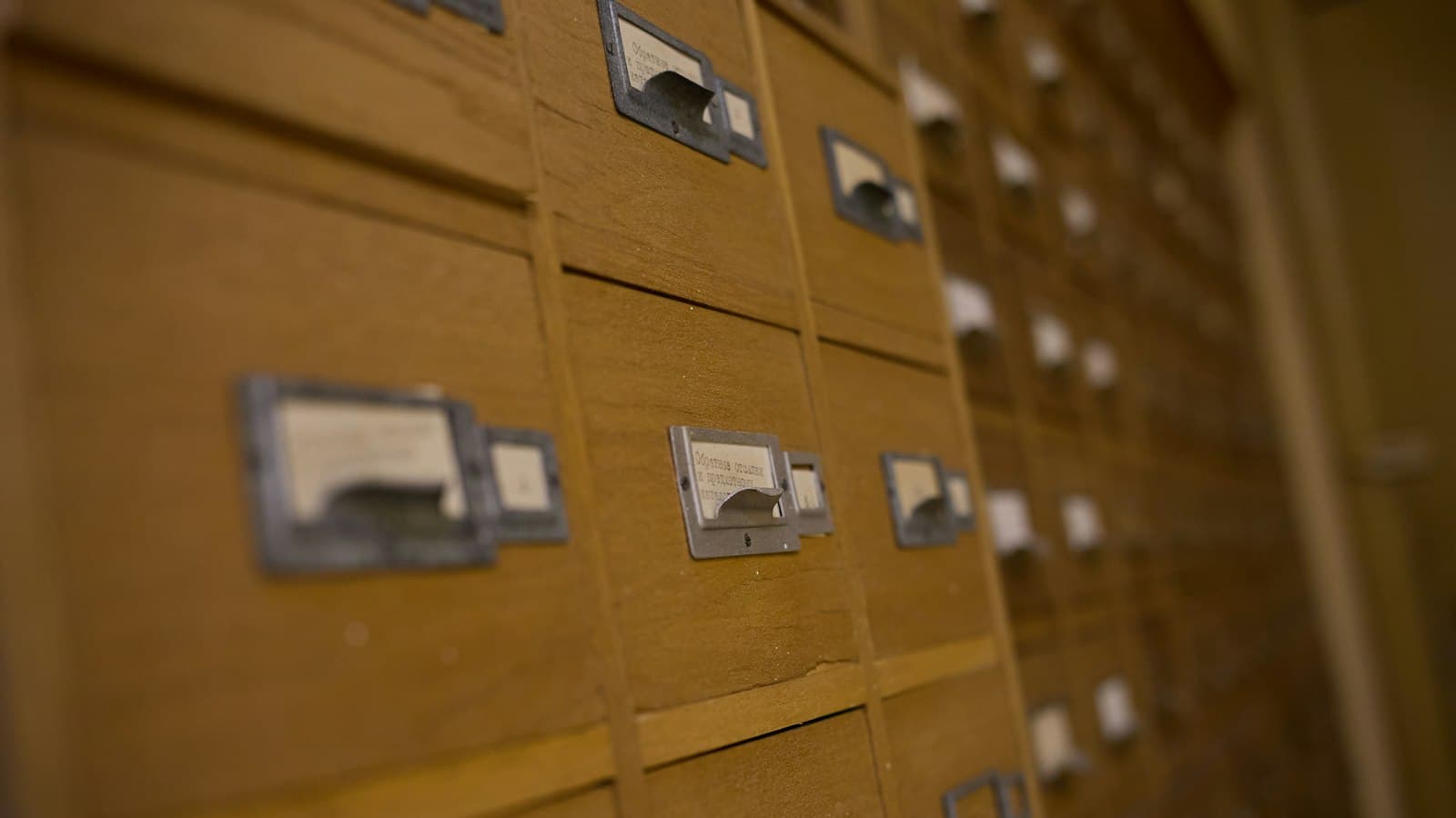 Rows of wooden library card catalogue drawers with metal label holders