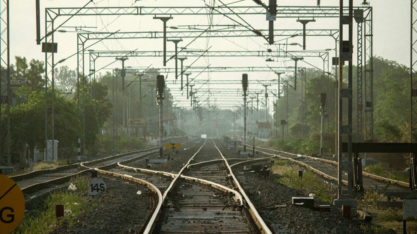 Railway tracks branching through switches under overhead electric lines and signal posts